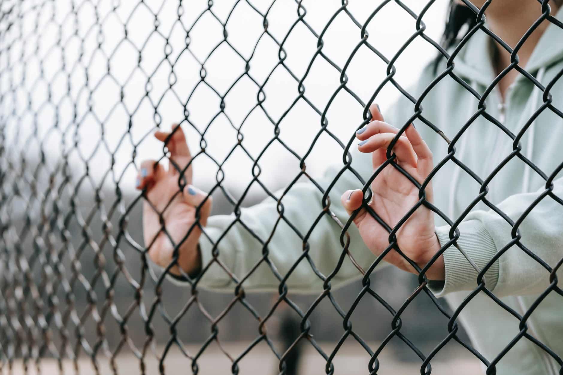 woman being held back by fence