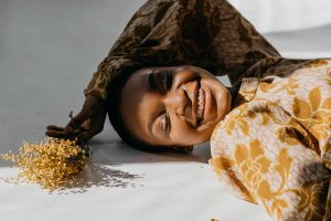 a happy woman in gold floral dress lying down